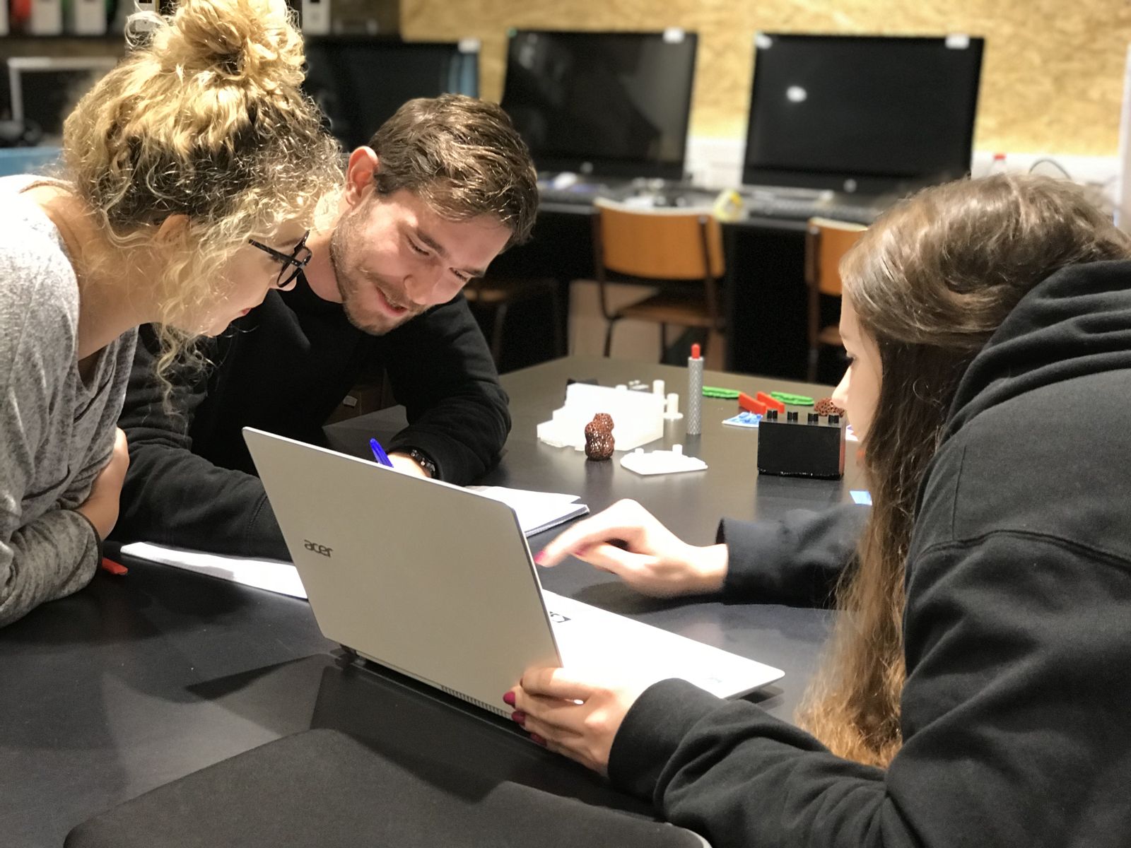 Students discussing a project around a laptop and 3D-printed prototypes